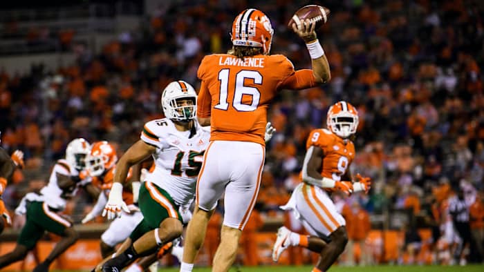 Clemson Tigers quarterback Trevor Lawrence (16) throws to running back Travis Etienne (9) against Miami Hurricanes defensive line Jaelan Phillips (15) during the first quarte at Memorial Stadium.
